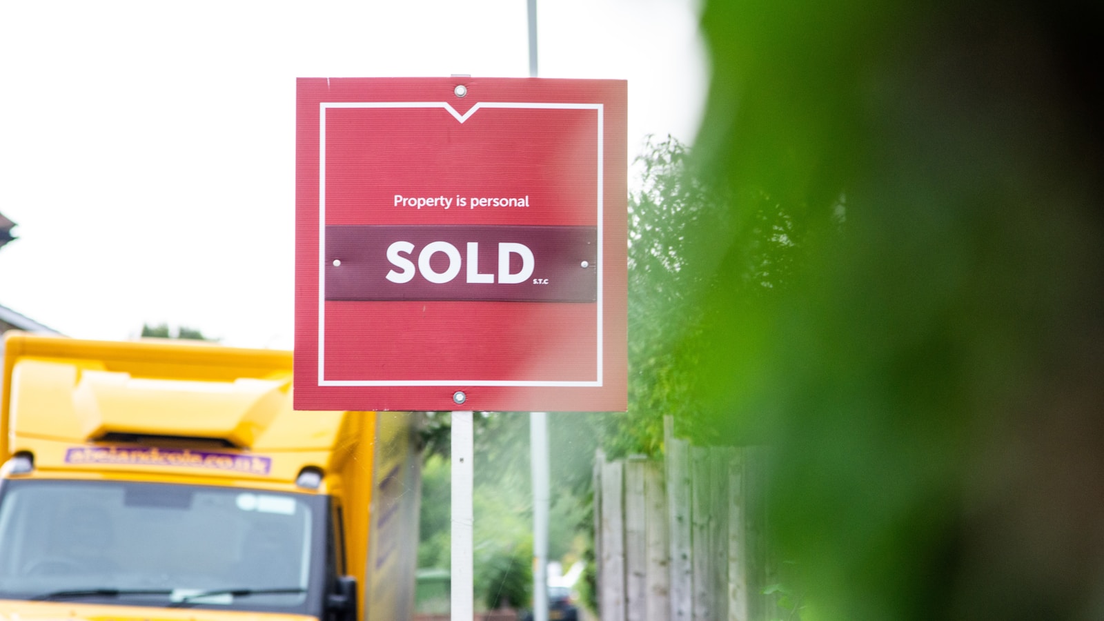 A red sold sign sitting on the side of a road