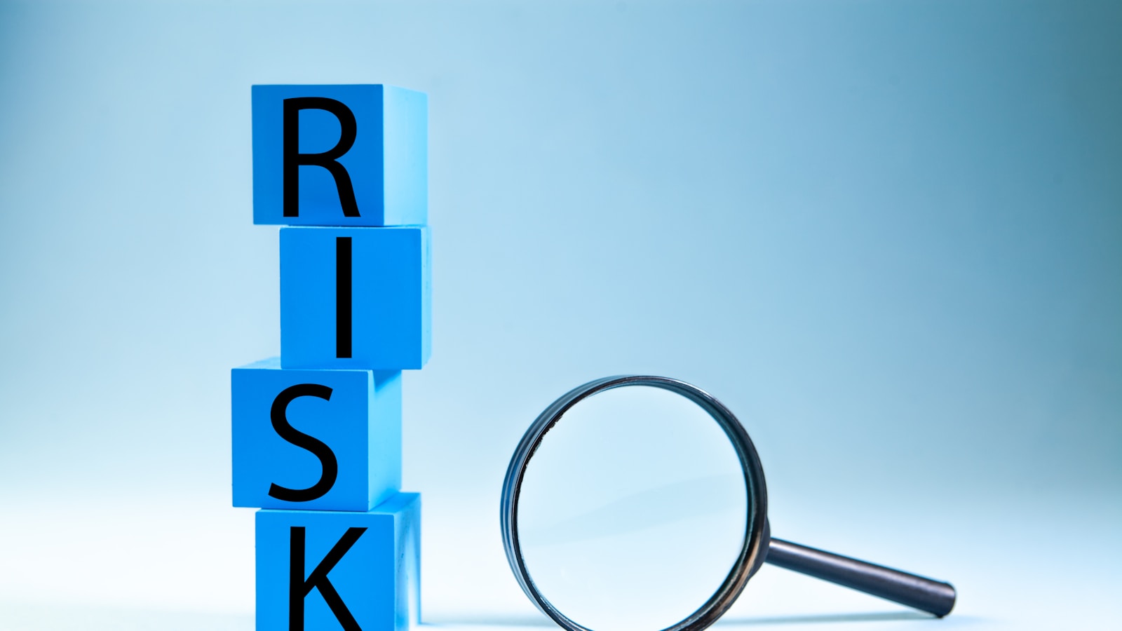 Blue blocks spelling risk next to a magnifying glass.