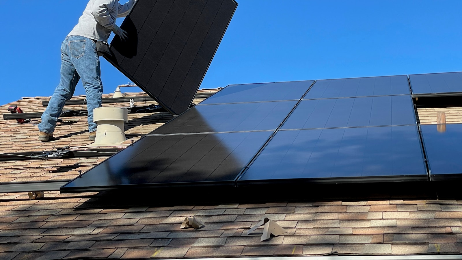 man in white dress shirt and blue denim jeans sitting on white and black solar panel